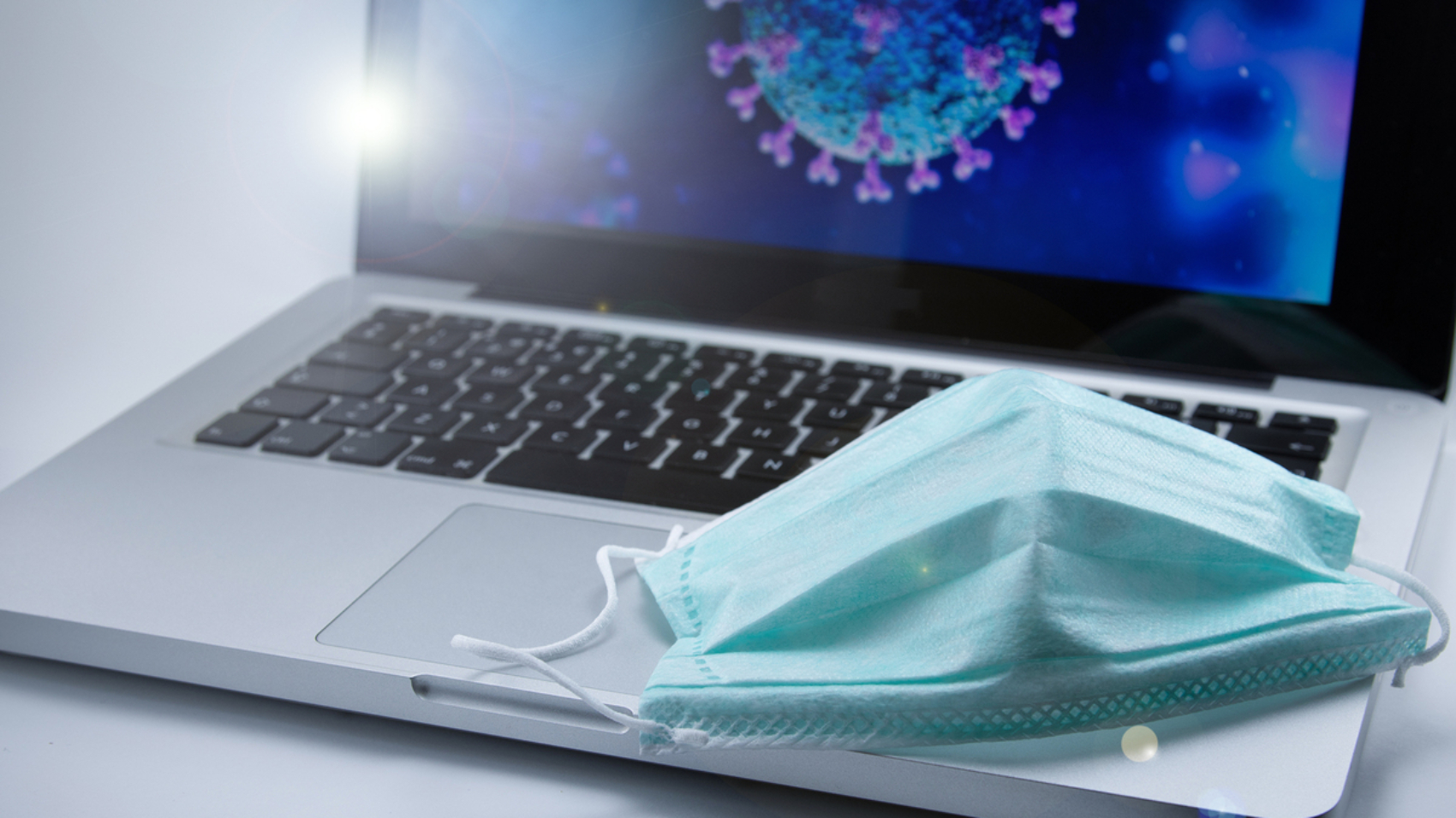 protective_face_mask_on_laptop_displaying_covid-19_coronavirus_cell_morphology_infection_outbreak_pandemic_by_rs74_gettyimages-1220667912_2400x1600-100854883-large